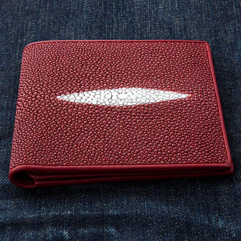 El exterior de un monedero de piel de estrella de mar vibrante en rojo, que muestra su textura única y pedregosa y la distintiva marca de perla blanca.