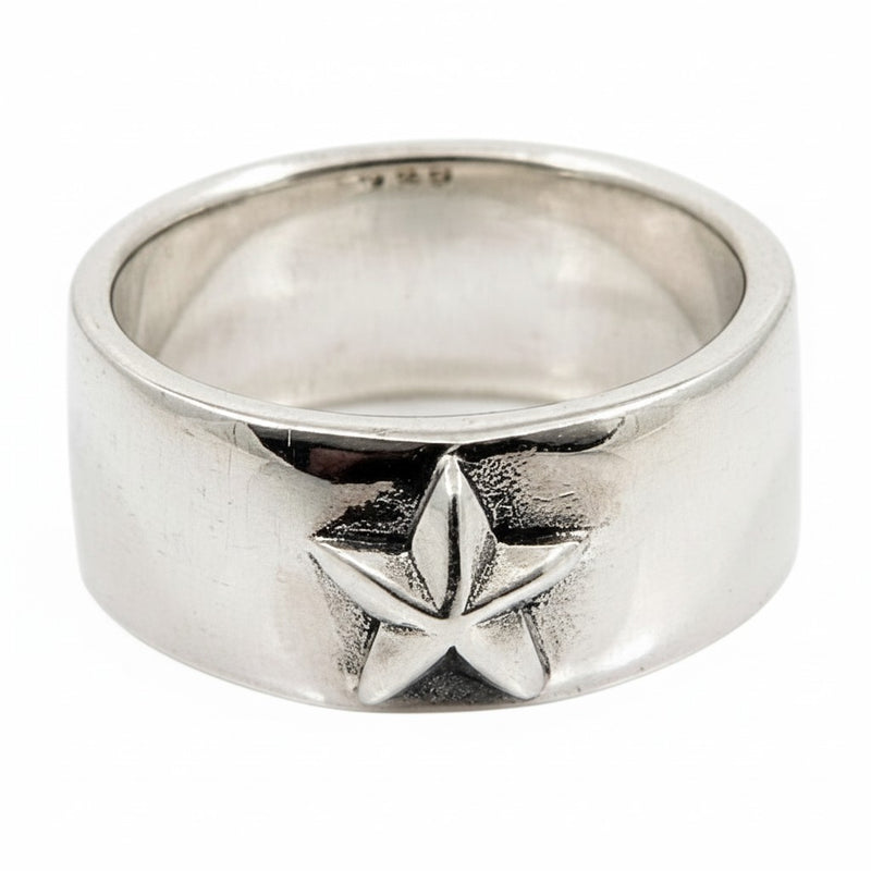 Una vista frontale di un anello a forma di stella in argento sterling con un emblema a stella a cinque punte, su uno sfondo bianco.