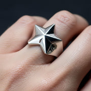 A man's hand wearing the large silver star ring, a classic piece of rocker jewelry.