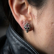 A close-up of a rocker wearing a sterling silver rose and skull earring, measuring 8mm by 11mm, captured in soft studio lighting.