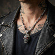 Close-up of a rocker wearing a sterling silver skull pendant featuring a red garnet stone.