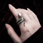 Håndlavet sølvslange ring båret på fingeren mod en mørk fløjl baggrund