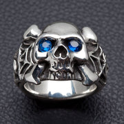 A solid 925 silver spider skull ring with blue eyes and crossbones on a black background.
