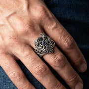 청바지 배경에 남자의 손에 착용된 파란 CZ 스톤이 있는 925 스털링 실버 드래곤과 검 링