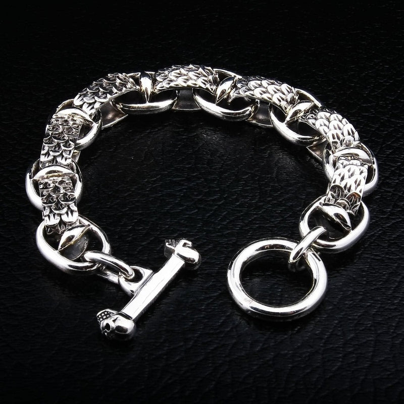 Armband aus Sterlingsilber mit Drachenschuppen und Totenkopf-Verschluss, präsentiert auf schwarzem Lederhintergrund