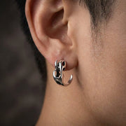 Sterling silver flame claw stud earring with 925 hallmark worn on a man's ear, featuring an edgy curved design with flame-inspired cutout details in a polished finish