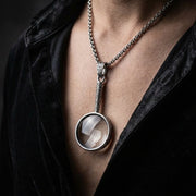 Sterling hopea suurennuslasi riipuskaulaketju, jossa on koristeellinen kaiverrettu kahva ja toimiva suurennuslasi, mallilla mustan samettivaatteen päällä.