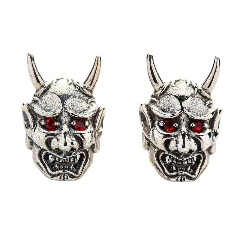 Una vista frontale della coppia di orecchini a maschera Oni in argento sterling, che evidenziano i loro occhi CZ rosso fuoco.