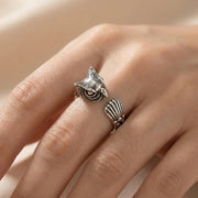 Anel de coruja em prata esterlina com penas detalhadas, usado no dedo de uma mulher, mostrando um design de banda aberta ajustável.