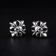 A pair of sterling silver skull and crossbones stud earrings with gothic filigree details, on a black background.