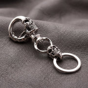 925 sterling silver crazy skull biker keychain with dual skull design resting on dark leather surface