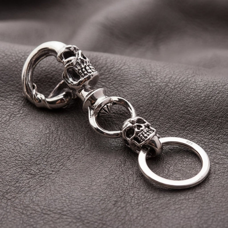 925 sterling silver galen skalle biker nyckelring med dubbla skalle design som vilar på mörk läderyta