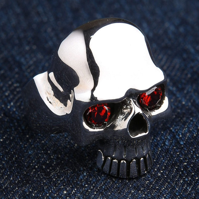 Sterling silver skull ring with red garnet eyes front view on blue denim background