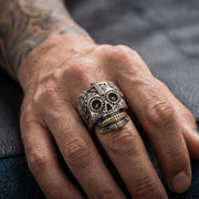 A close-up of a biker wearing a large sterling silver sugar skull ring, highlighting the 25mm by 30mm face size and detailed craftsmanship under soft studio lighting.