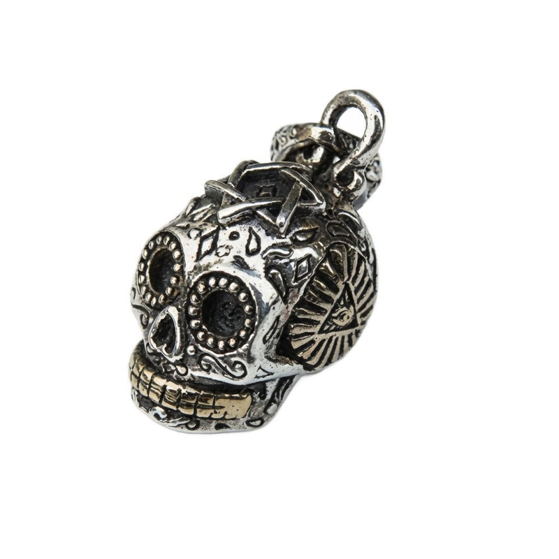 Colgante de calavera de azúcar de plata esterlina con acentos de latón que muestra intrincados grabados del Día de los Muertos y detalle del Ojo que Todo lo Ve.