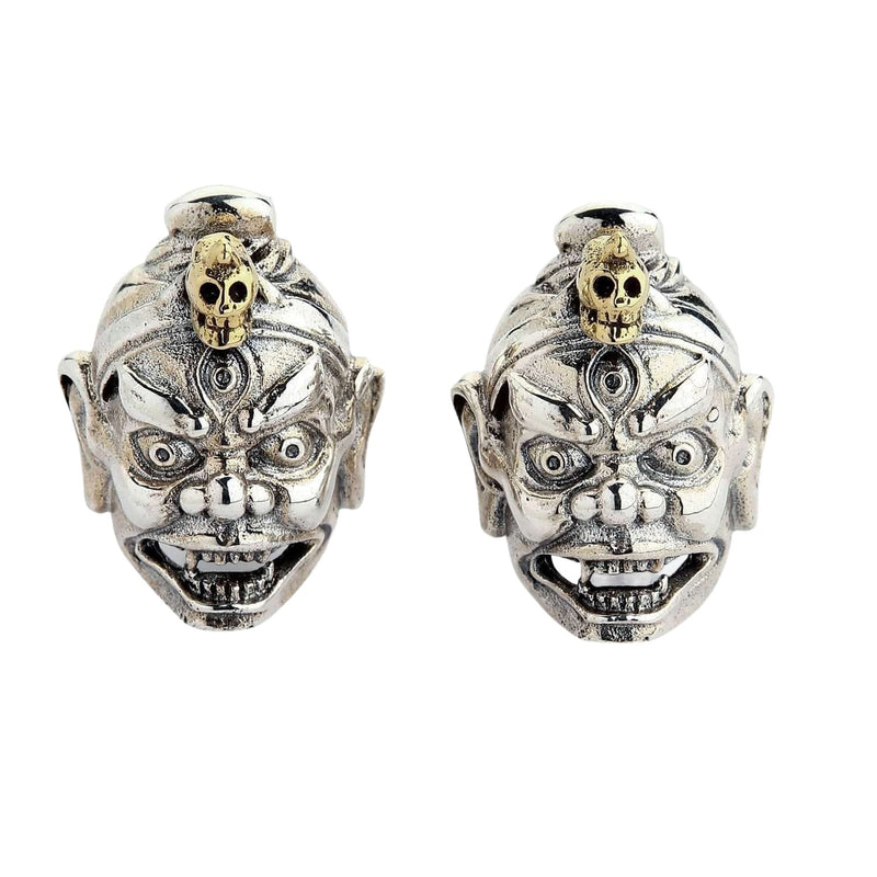 Una vista frontal de los aretes de aro de máscara de demonio tibetano de dos tonos, mostrando la cara de plata y el cráneo de latón.
