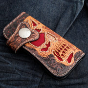 A hand-tooled leather skull wallet with a striking, fiery red stingray inlay and intricate floral patterns.