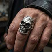 一個人的手穿著巨大的硬頭骨環,展示了它的粗糙,戰鬥的結構。