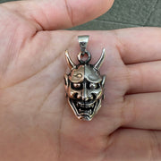 A front view of the two-tone Oni mask pendant, showcasing the split sterling silver and copper face.