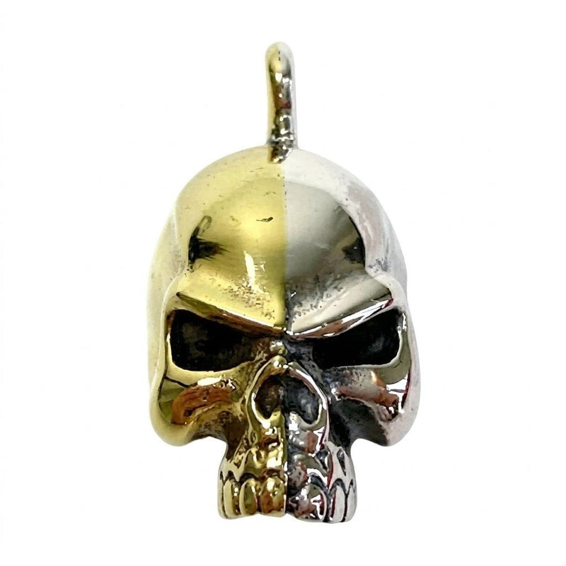 Front view of a skull pendant bisected by a hard vertical line, with one half gold brass and the other sterling silver.