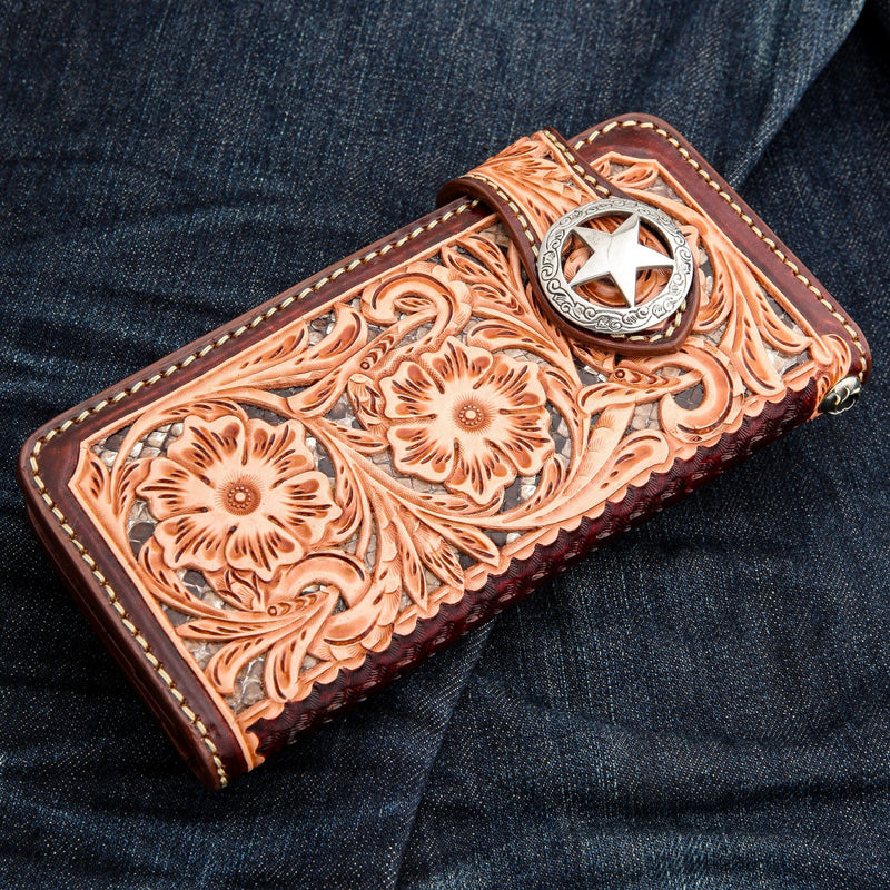 Vista inclinada de la cartera de cuero marrón para motociclista que muestra un intrincado grabado floral y un inserto con textura de piel de serpiente.