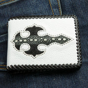 The handmade white leather biker wallet with a black stingray gothic cross inlay, resting on blue jeans.