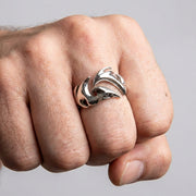 एक आदमी की मुट्ठी चौड़ी चांदी की जनजातीय अंगूठी पहने हुए, जो इसके प्रमुख बयान शैली को प्रदर्शित कर रही है।