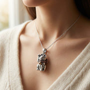 A realistic close-up lifestyle shot of a woman wearing a sterling silver Japanese Maneki Neko cat pendant, showcasing the detailed lucky cat design and 34mm length under soft studio lighting.