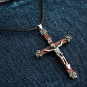 A large and detailed wood crucifix pendant with a solid sterling silver figure of Jesus and ornate floral end caps.