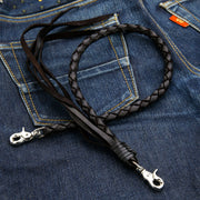 The black braided leather wallet chain with silver-tone clasps, coiled on the back pocket of a pair of blue jeans.