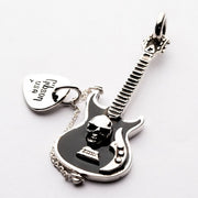A handcrafted black skull guitar pendant in solid 925 silver with a dangling pick charm.