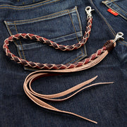 A full view of the two-tone black and brown braided leather wallet chain with tassels, resting on the back pocket of blue jeans.