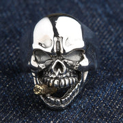 A solid sterling silver cigarette skull ring with a detailed, 14K gold-plated cigarette, shown on a denim background.