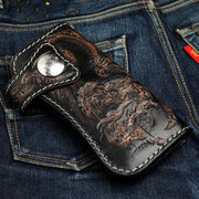 The gothic dragon long wallet resting on denim jeans, showing the snap closure.