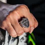 A man's hand wearing the large, heavy gothic fleur de lis ring, showing its scale.