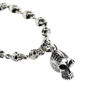 A solid sterling silver punk skull bracelet with a chain of detailed skulls and a larger, black-jeweled skull charm.