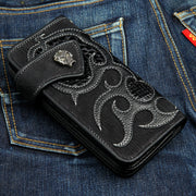 A custom biker wallet made from rugged black shark skin with a shiny black lizard skin flame inlay and a solid sterling silver skull snap.
