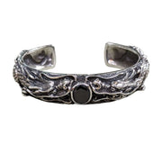 Front view of heavy sterling silver cuff bracelet featuring two dragons facing a central black stone.