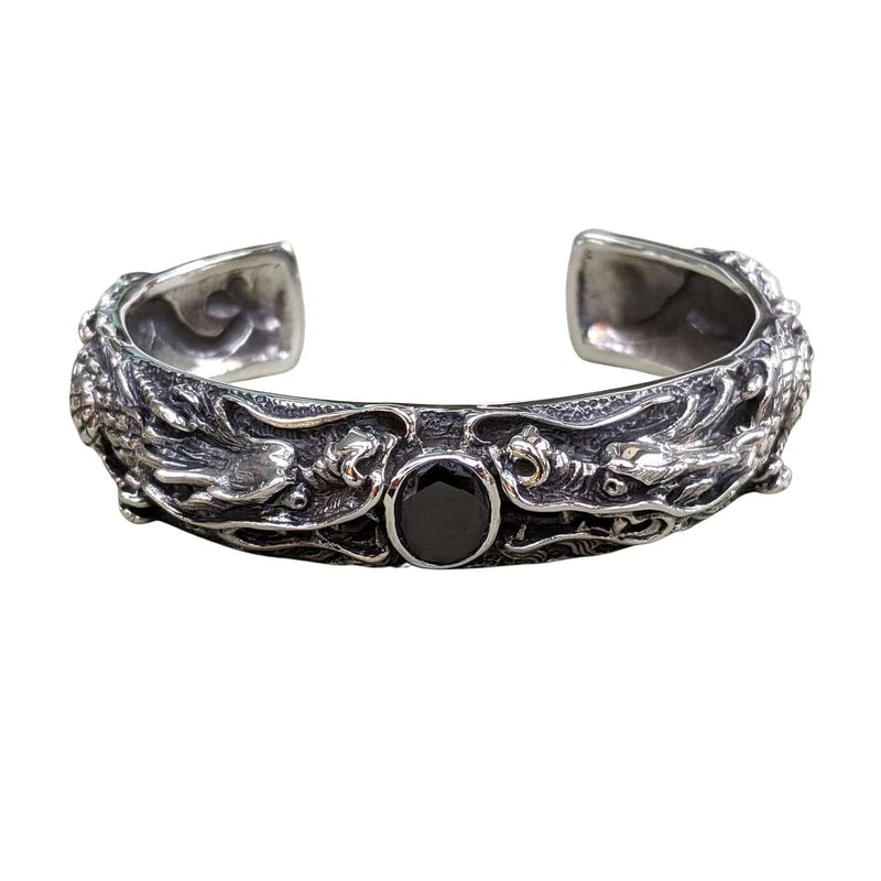 Vorderansicht eines schweren Armreifs aus Sterlingsilber mit zwei Drachen, die einem schwarzen Stein in der Mitte gegenüberstehen.