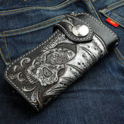 The winged skull biker wallet shown folded and resting on a pair of denim jeans.