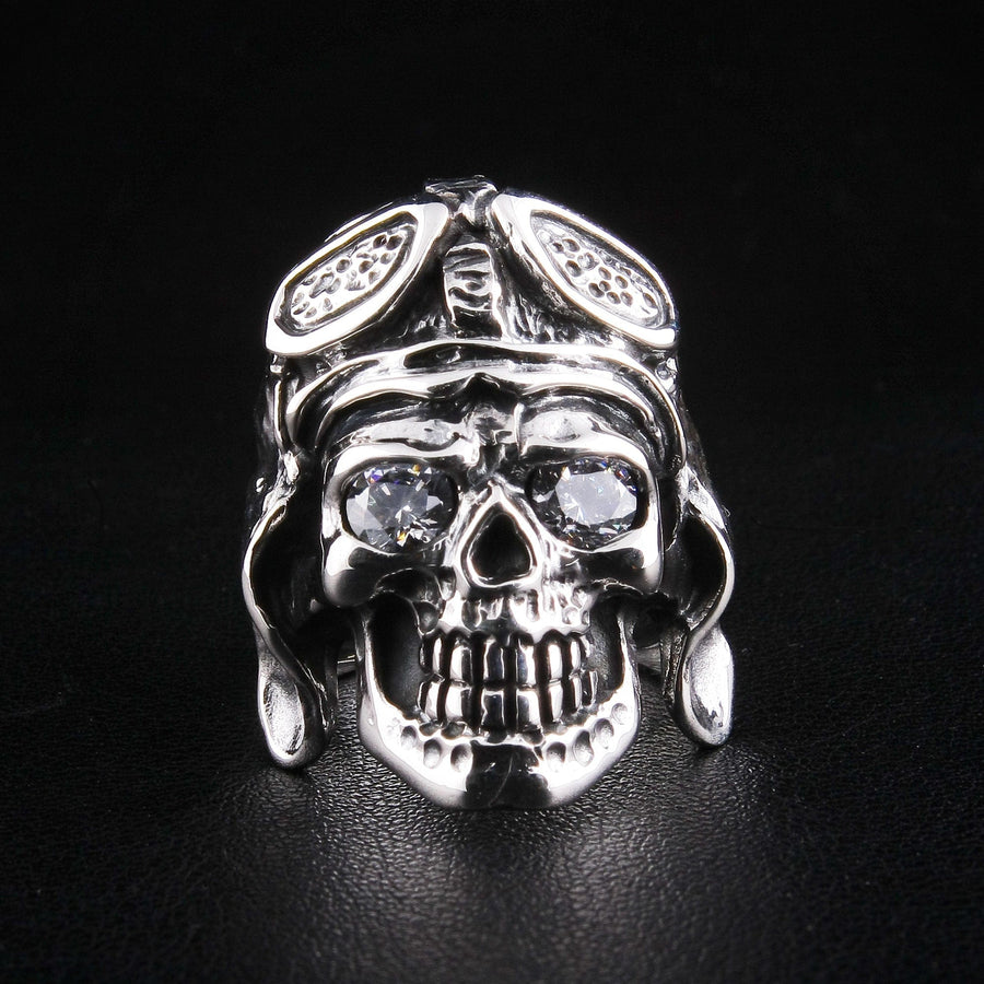 Una vista frontal directa de un anillo de calavera alemán de plata esterlina sólida, que muestra claramente sus ojos de diamante brillantes y el casco de piloto detallado.