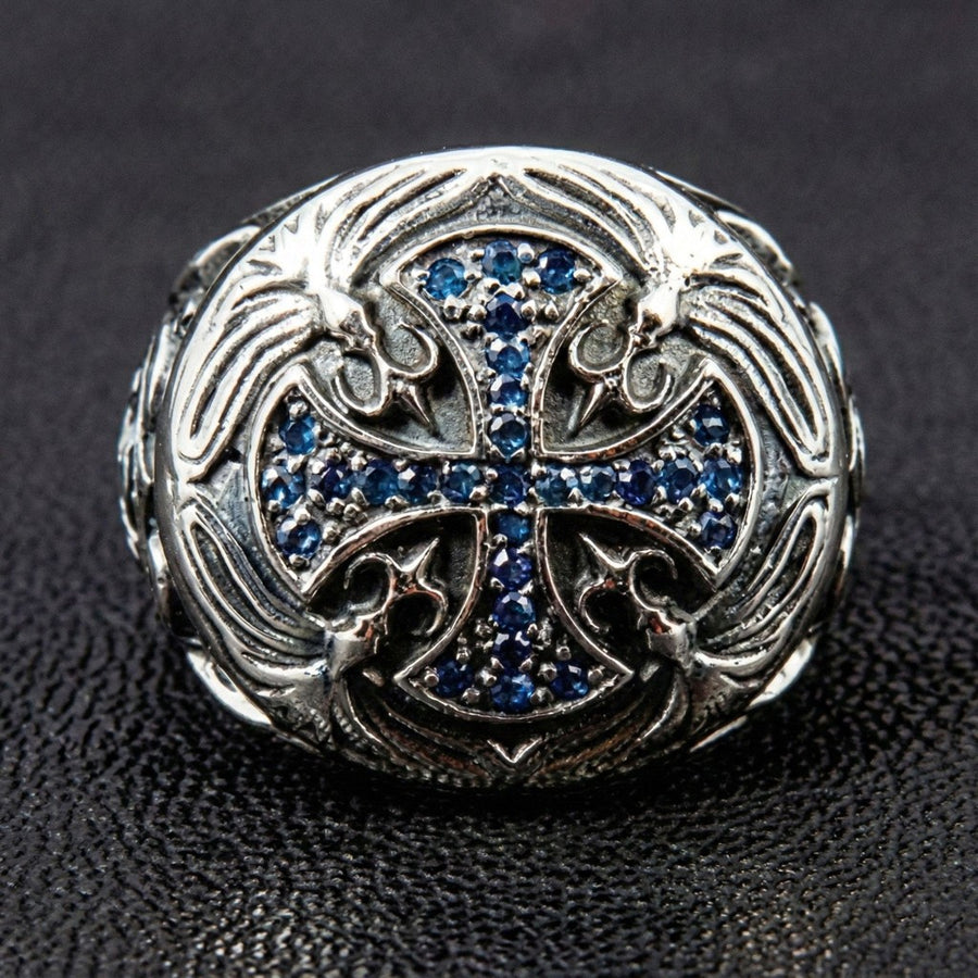 Vista dall'alto dell'anello con croce dei Cavalieri Templari, impreziosito da pietre CZ zaffiro blu incastonate a pavé e dettagli floreali incisi in argento.