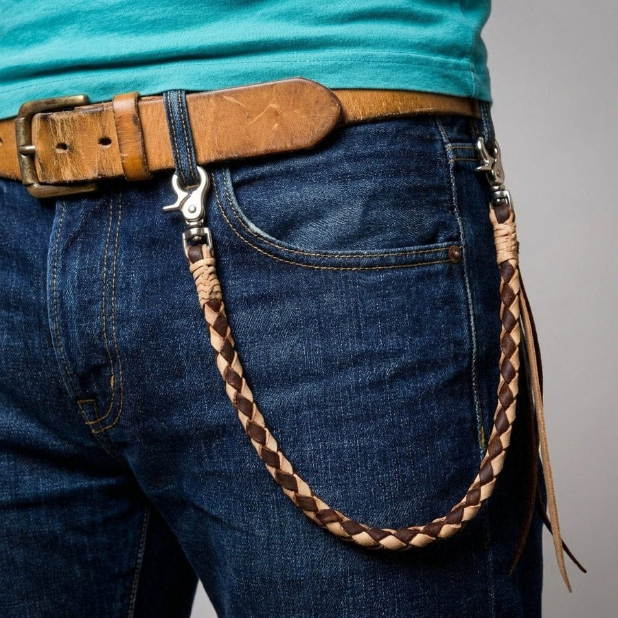 Chaîne de portefeuille en cuir tressé bicolore attachée à la boucle de ceinture et à la poche du jean montrant comment elle se drape.