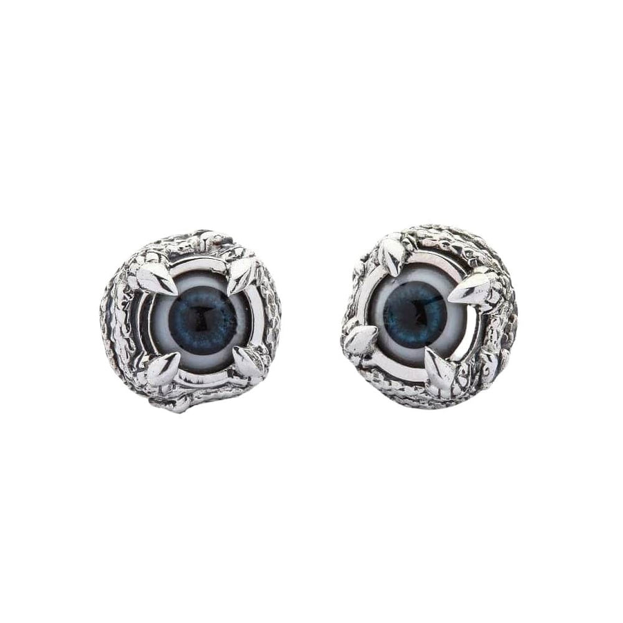 Une paire de boucles d'oreilles clou en argent sterling gothique en forme d'œil de griffes, vue de face montrant le centre en œil bleu et le détail de la monture en argent en forme de griffe.