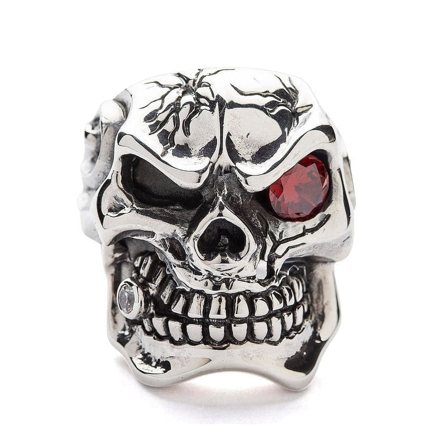 Vista anteriore dell'anello per teschio in argento sterling pesante con crepe, che mostra il dettaglio dell'occhio di granato rosso e della fronte crepata.