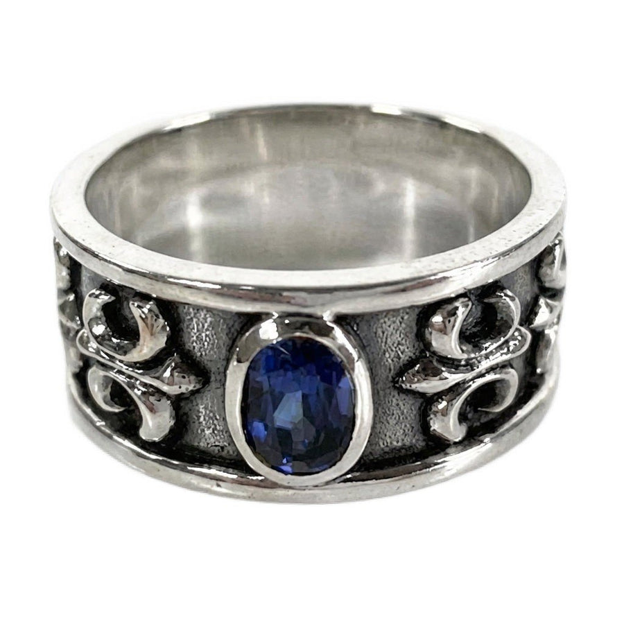 Bague anneau pour homme en argent sterling ornée d'une pierre ovale bleu saphir et de détails texturés fleur de lys sur les côtés.