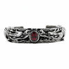 Un brățară din argint sterling masiv, cu un design complex, prezentând două dragoni sculptați cu măiestrie care păzesc o piatră ovală centrală de granat roșu.