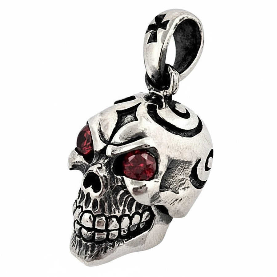 Vue oblique du pendentif tête de mort en argent sterling, montrant les gravures tribales et les yeux en pierre précieuse rouge.