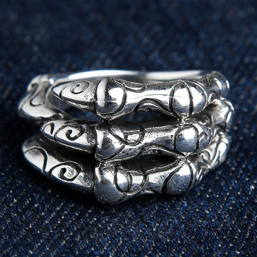 Gothic dragon claw ring in 925 sterling silver showing four detailed talons with tribal engravings on blue denim background