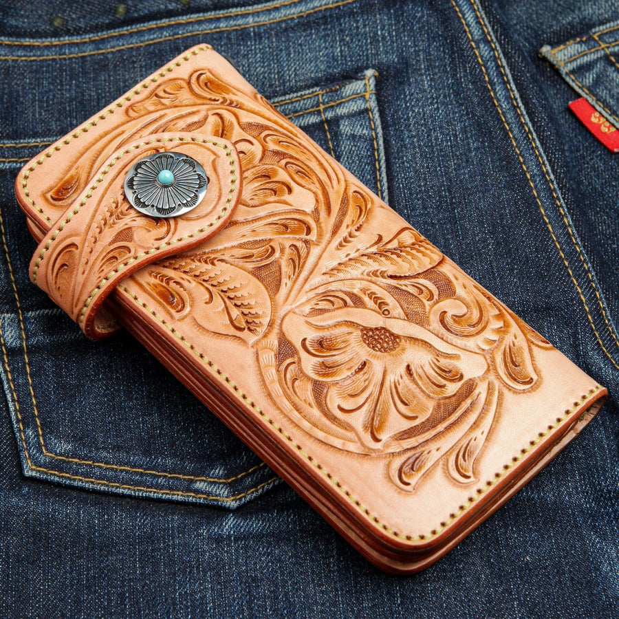 A handcrafted, hand-tooled Japanese floral leather wallet, shown on denim.
